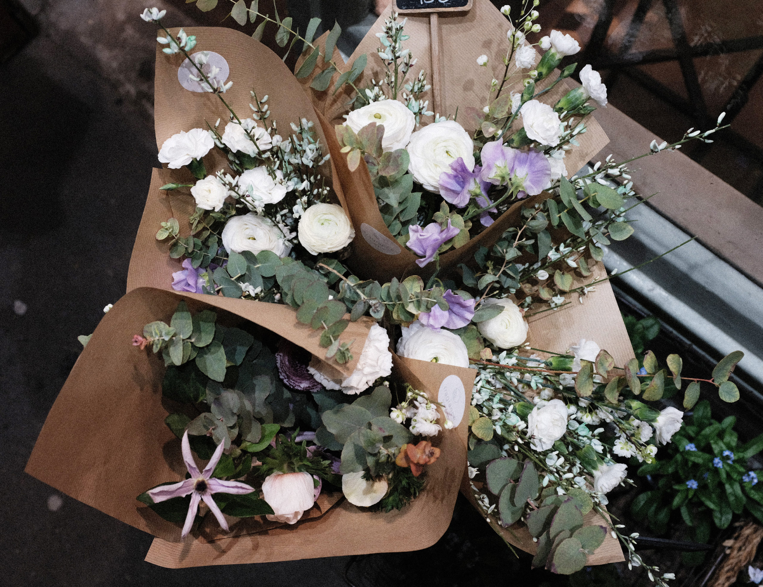 Composition de fleurs fraîches et emballage kraft (genêt, renoncules, eucalyptus, mini-œillets, pois de senteur, prunus)